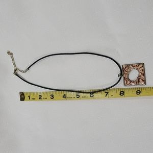 Necklace, black cord with brown and tan pendant.